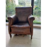 An antique leather club chair in distressed manner with scrolling arms (H95cm W71cm D31cm SH43cm)