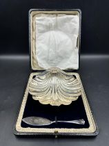 A silver scallop butter dish with a company knife, both hallmarked for Sheffield 1920 and 192,