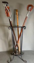 A selection of two walking sticks and two brown leather shooting sticks in a wrought iron stick