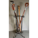A selection of two walking sticks and two brown leather shooting sticks in a wrought iron stick