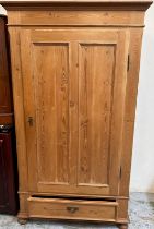 A pine single door wardrobe opening to a single cross hanging rail with drawer under (H178cm