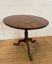 A circular oak tilt top table on turned central support and splayed tripod legs (H66cm Dia71cm