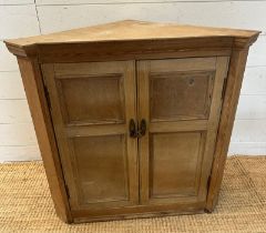 A pine two door corner cabinet with brass drop handles opening to two shelves (H67cm W68cm D38cm)
