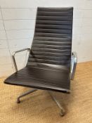 A brown leather and aluminum lounge armchair by Charles Eames for Vitra