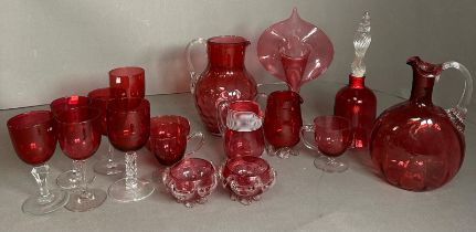 A selection of cranberry Art glass to include jugs, glasses and a bell