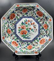 An Imari palette octagonal charger with a painted peony central shield and relief with gilt rim