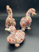A set of three Chinese china ducks in various poses.
