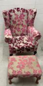 A wing back arm chair upholstered in a floral pattern and an accompanying stool