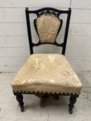 An ebonised and carved bedroom chair with cream floral upholstery