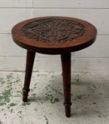 A vintage carved tripod stool on turned legs