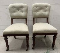 A pair of mahogany aesthetic movement hall chairs on castors in a pale green upholstery