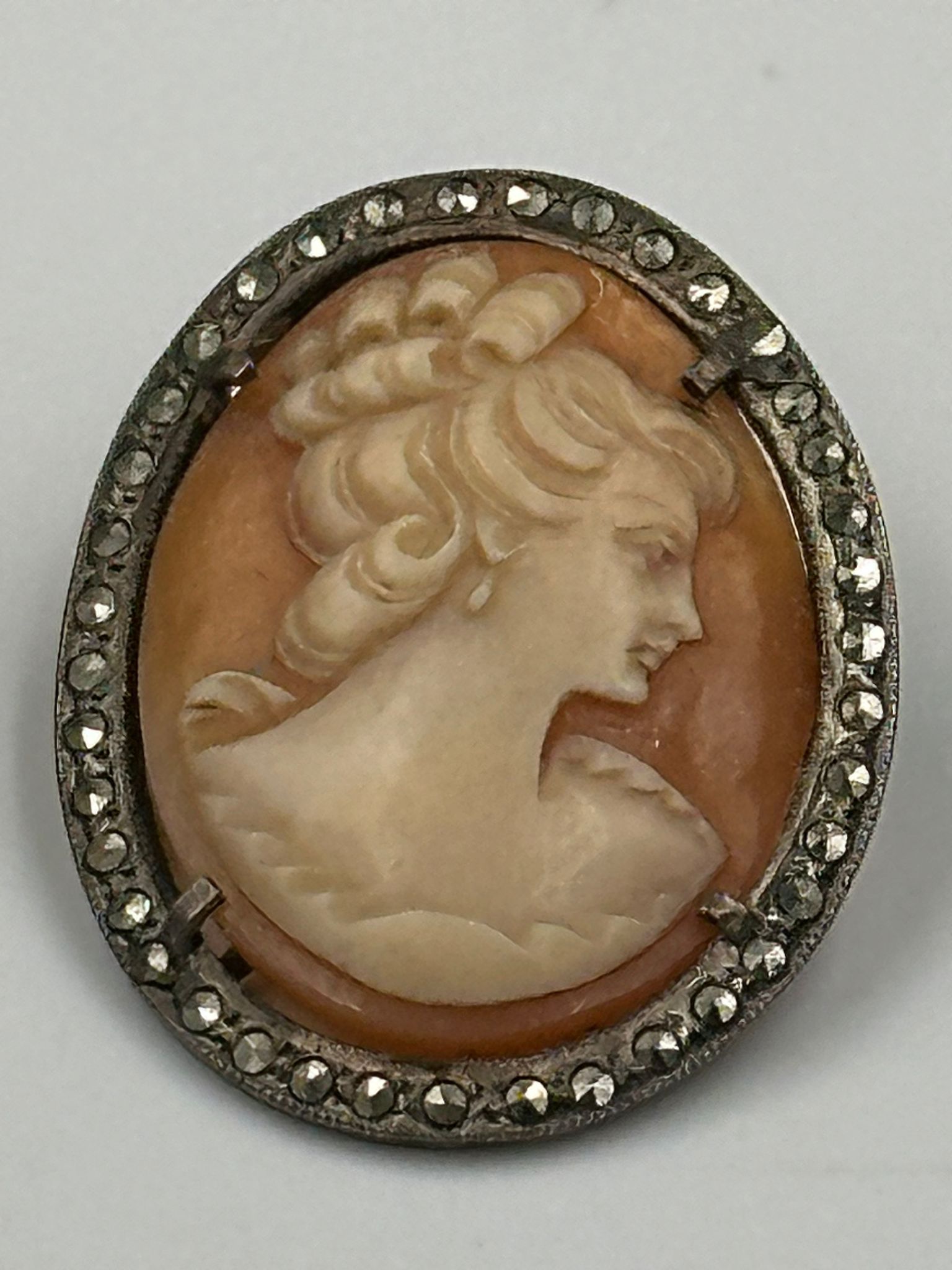 A vintage cameo on silver brooch with lady in classical in pose.