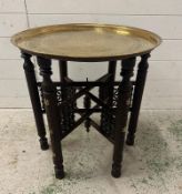 A brass topped Indian tea table on folding legs with mother of pearl inlay