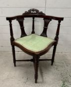 An Edwardian mahogany corner chair on turned legs with green upholstered seat