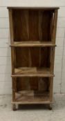 A three tier wooden shelving unit with X frame sides (H122cm W51cm D26cm)