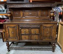 An oak Jacobean style heavily carved court cupboard with three central drawers flanked by
