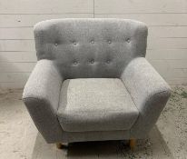 A grey upholstered contemporary button back arm chair