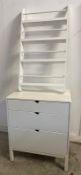 A white contemporary chest of three graduating drawers and a matching four shelf wall hanging