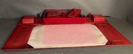 A red leather desk top set comprising of a writing surface, blotters, document tray and storage pots