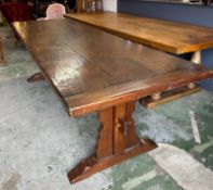 A large oak three plank refectory table on carved legs with pegged cross stretcher by Batesy
