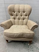 A button back armchair on turned legs and brass wheels