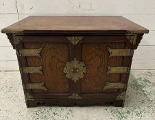 A Korean style hardwood cabinet with brass hinges and fittings the cupboard opening to a single