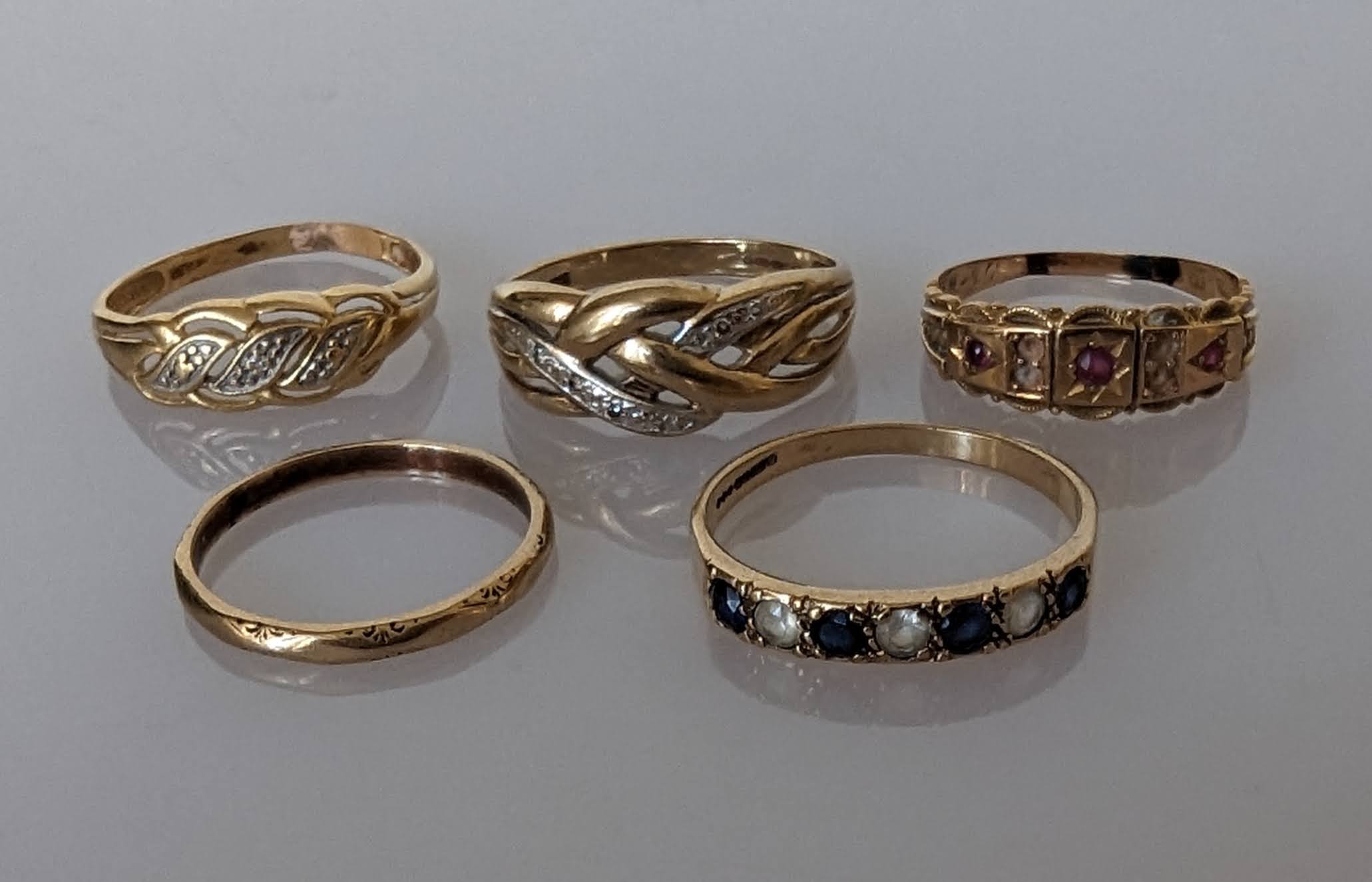 An assortment of five 9ct gold gem-set rings, one wedding band