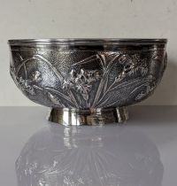 A Chinese silver circular bowl with banded rim, embossed flowers on a planished ground