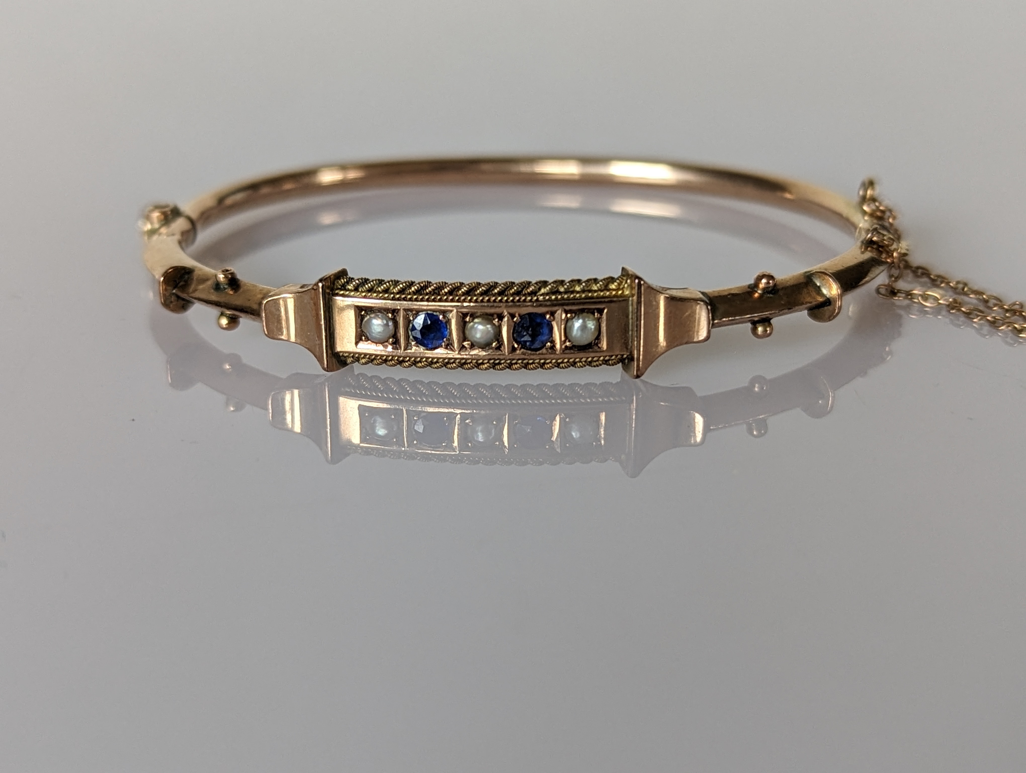 An Etruscan-style gold hinged bangle with sapphire and seed pearl decoration, stamped 9ct - Image 2 of 4