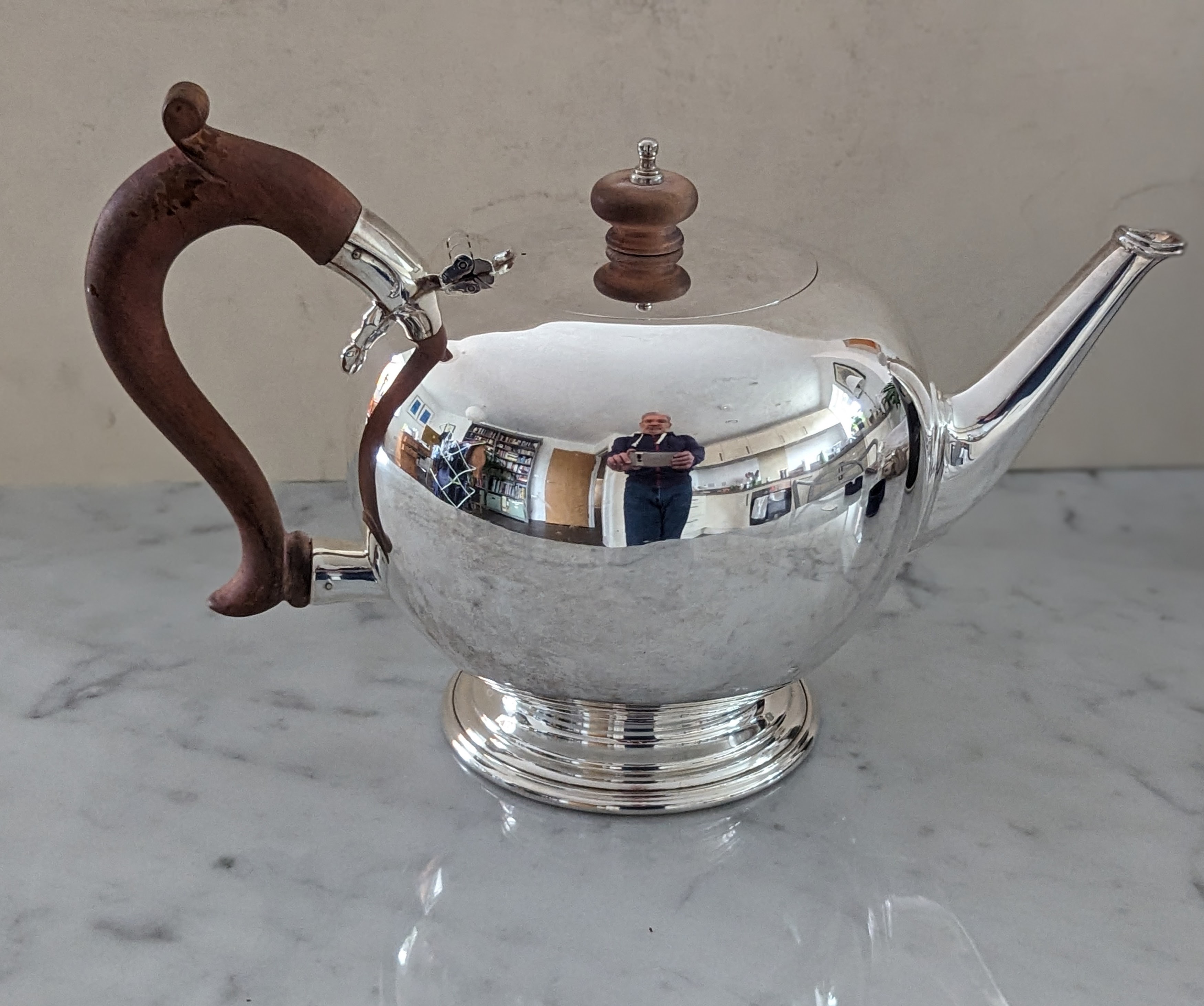 A globular silver tea pot with fruitwood handle and knop on a spreading foot, 17 cm H