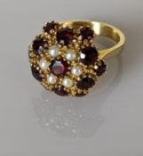 An Edwardian ruby and pearl cluster dress ring on a yellow gold setting, stamped 750, size O, 8.4g