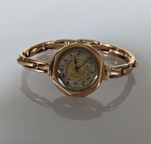 A 1920s ladies manual wristwatch with Arabic numerals, hexagonal rose gold case and elastic strap