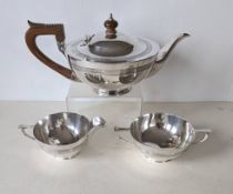 An Edwardian silver tea service of squat form with reeded bands, carved wood handle and knop