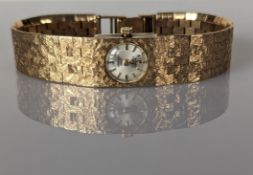 A vintage Oriosa ladies watch with champagne dial, baton markers on a 9ct yellow gold textured brick
