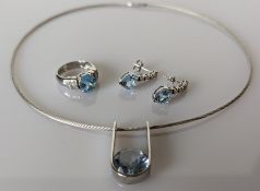 A custom made pendant set with a round mixed-cut pale blue topaz, 14mm diameter, set to white wire U