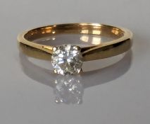 A solitaire diamond ring on a yellow gold claw setting, the round brilliant cut diamond approximatel