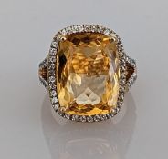 A citrine dress ring on a yellow gold split shank setting surrounded by cubic zirconia decoration