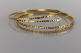 Four yellow gold bangles with bark-effect texture, each 65mm, stamped 750, 23.5g