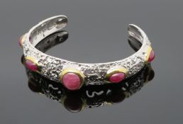 Designer Armspange, besetzt mit 5 Rubin-Cabochons, Ringschiene in reliefiertem Dekor, durchbrochen