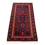 An early 20th century Turkish hand woven red ground geometric design carpet, 225 x 125cm.