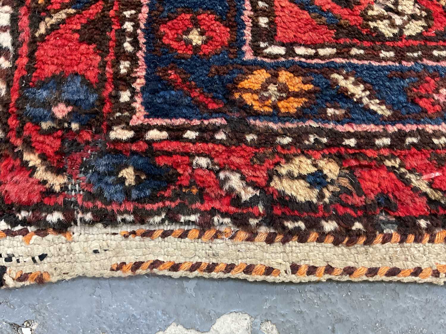 An antique Persian red ground carpet, with central triangular medallion surrounded by blue and red - Image 3 of 4