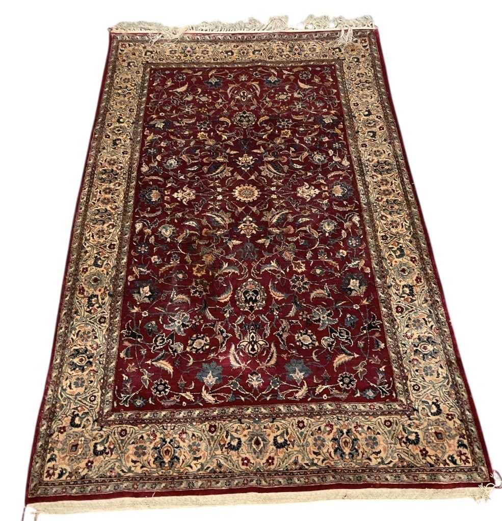 A Persian style hand woven silk red ground floral decorated carpet, with central red ground