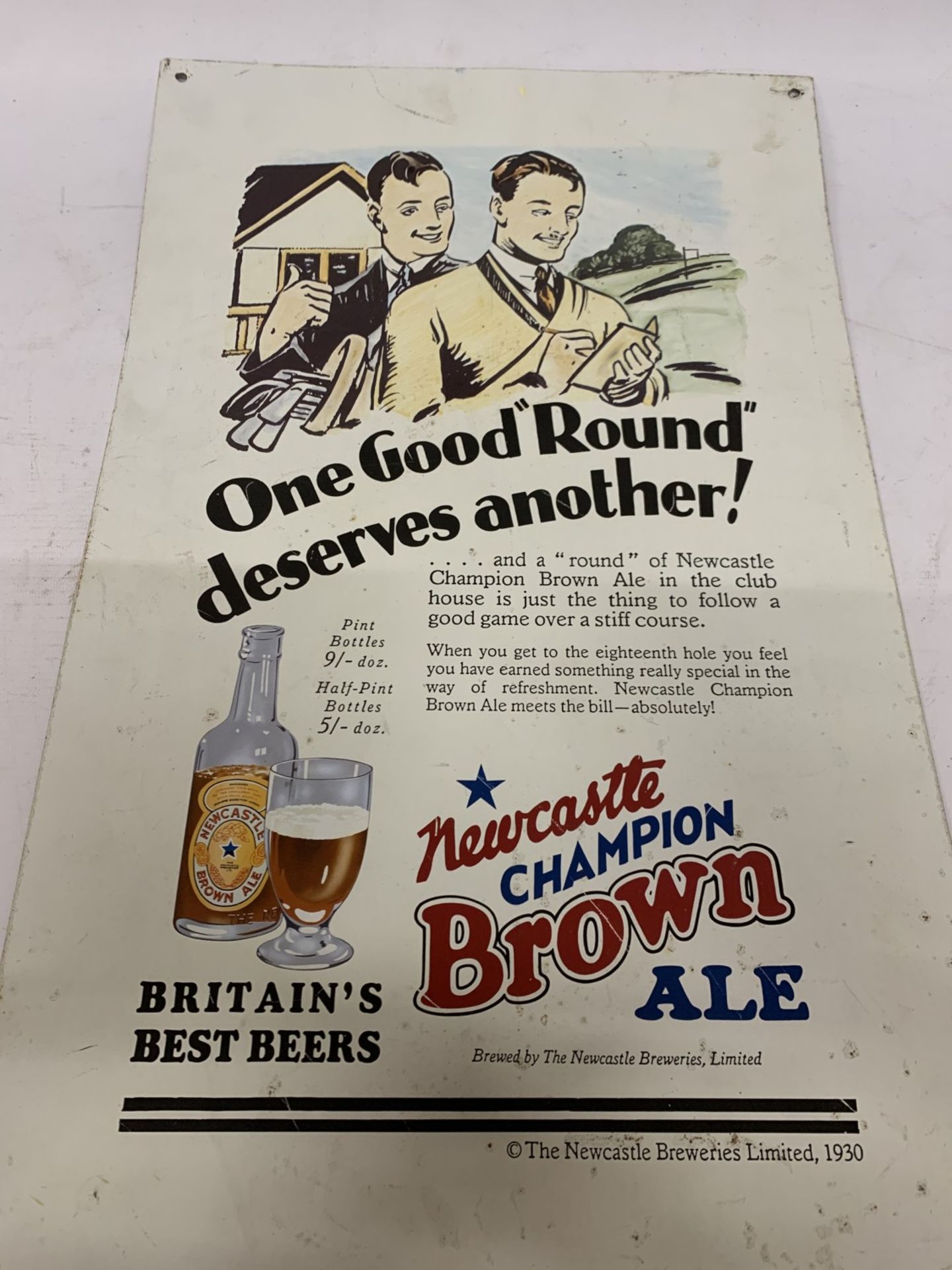 A LARGE VINTAGE TIN NEWCASTLE BROWN ADVERTISING SIGN 'ONE GOOD ROUND DESERVES ANOTHER' 62CM x 39CM
