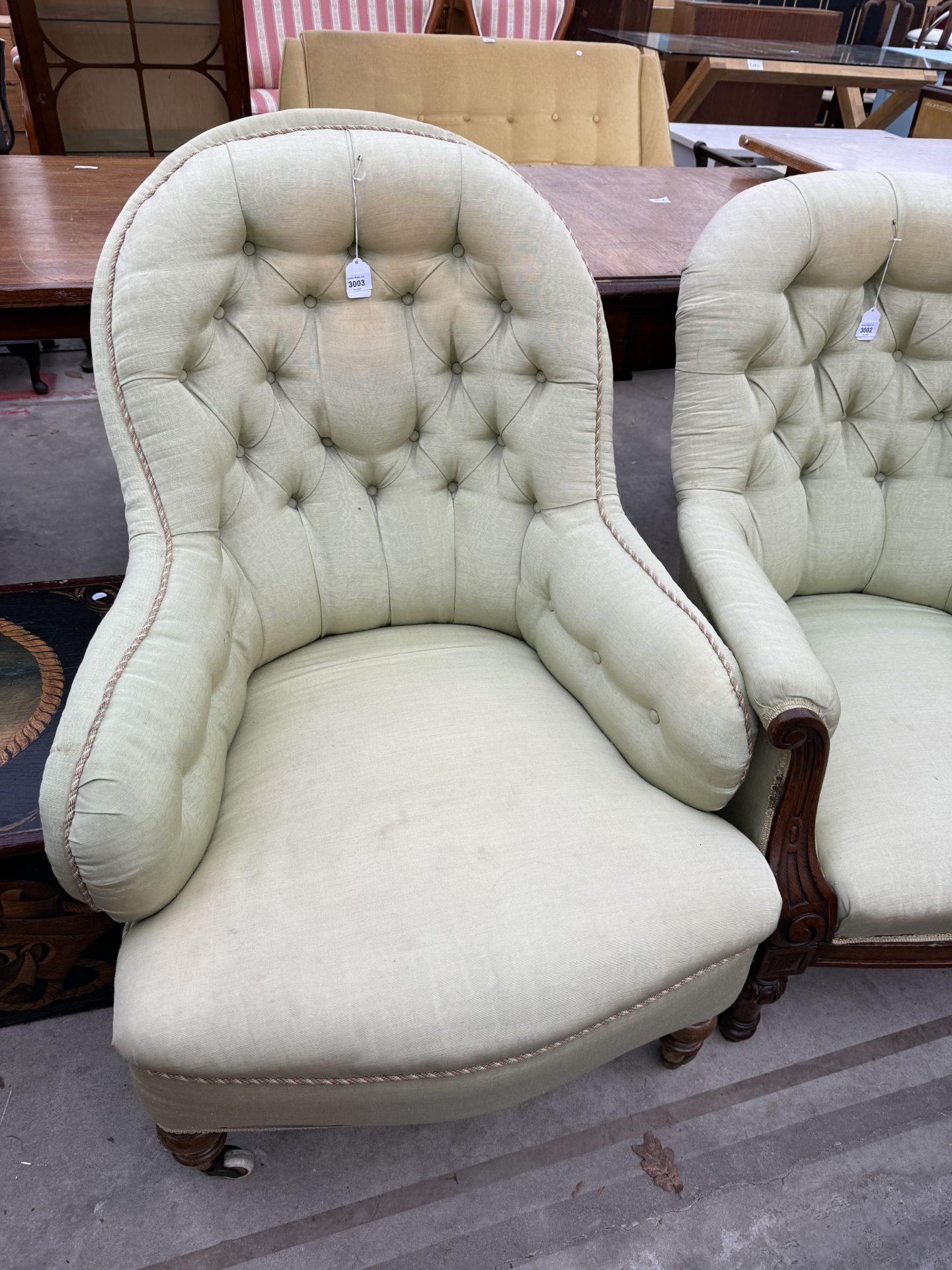A VICTORIAN BUTTON BACK LOUNGE CHAIR WITH SHAPED ARMS ON TURNED FRONT LEGS