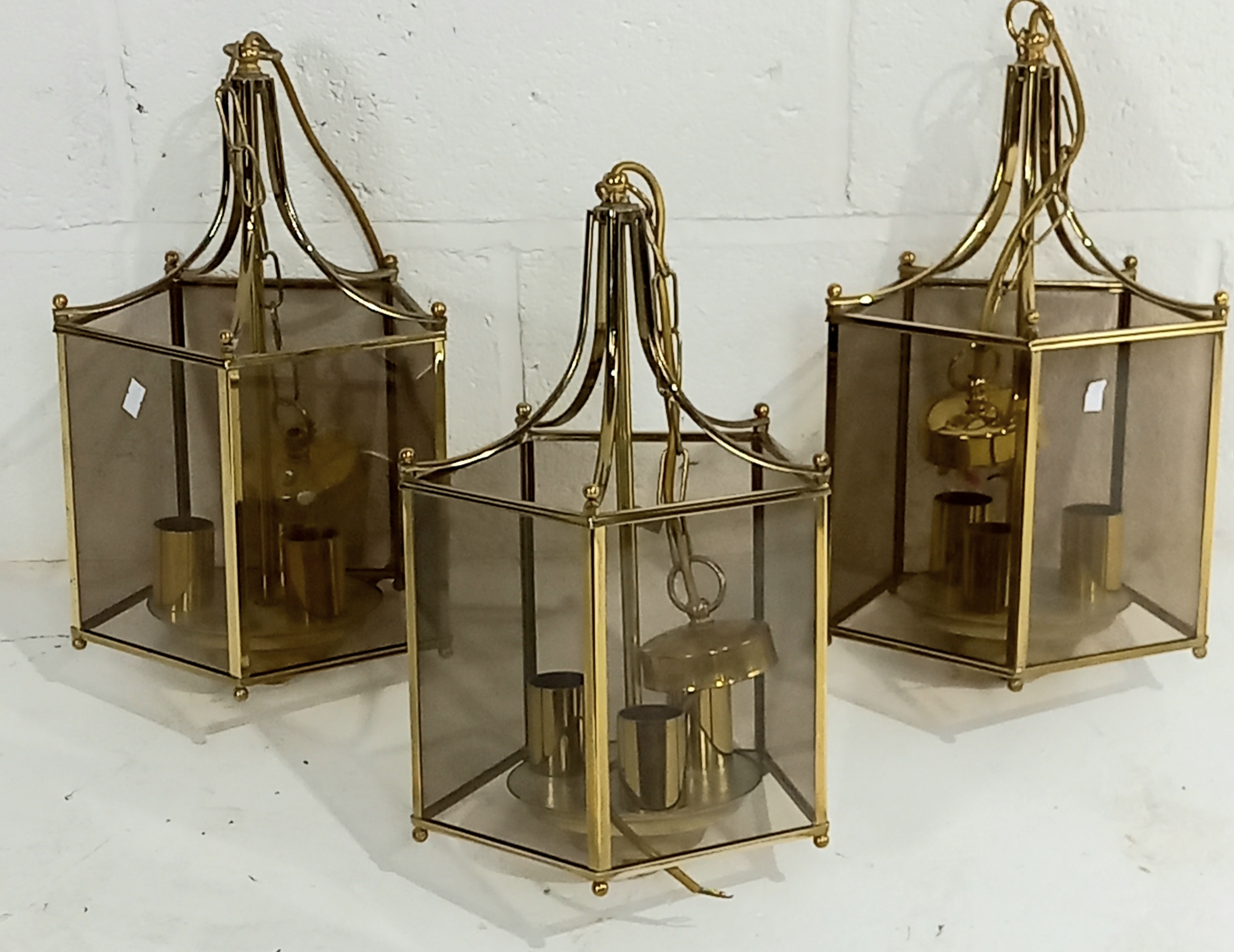 A set of three smoked glass and brass lantern style pendant light fittings.