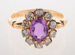 A pink sapphire and diamond cluster ring, claw set to the centre with an oval-cut pink sapphire,