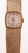 Omega a lady's 9K gold wristwatch the silvered cushion dial signed Omega and having raised black