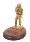 A 20th Century brass model of an airman in a standing position holding a rucksack,