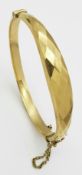 A 9K GOLD HINGED BANGLE WITH GRADUATED AND FACETED FRONT . 9.6gms