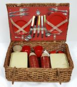 A vintage wicker picnic basket with buckle fasteners, containing two original Thermos flasks, and